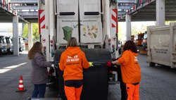 Teilnehmerinnen lassen sich die Schüttung am Müllwagen erklären